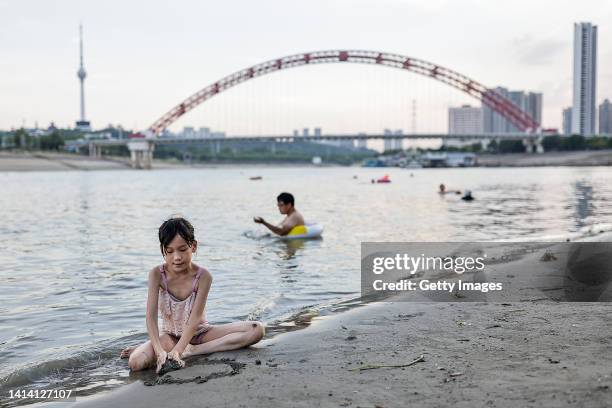 Girl plays on the beach beside the Hanjiang River during a heat wave on August 10, 2022 in Wuhan, Hubei Province, China. According to local media...