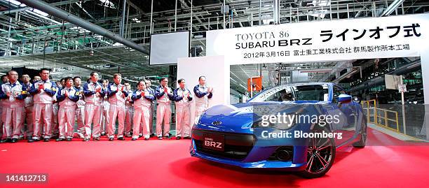 Fuji Heavy Industries Ltd. Subaru BRZ sports coupe is driven as employees applaud during a line-off ceremony for the Subaru BRZ and Toyota 86 sports...