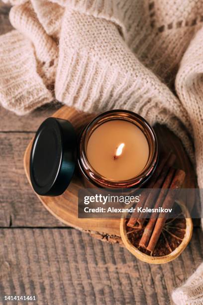 candle in small amber glass jar with wooden wick on wooden stand on background. top view - candel stockfoto's en -beelden