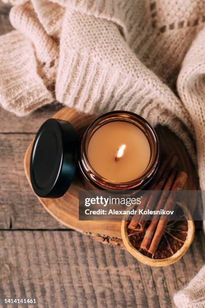 candle in small amber glass jar with wooden wick on wooden stand on background. top view - winter candlelight stock pictures, royalty-free photos & images