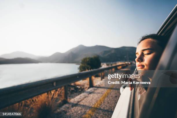 little girl looking out of car on a road trip. - freie fahrt stock-fotos und bilder