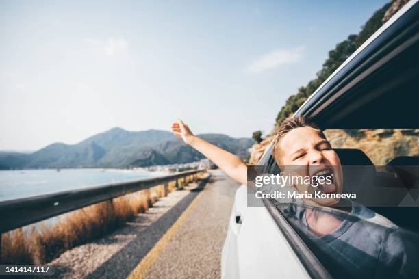 boy enjoying the wind blowing his hair in the back seat of the car. little boy looking out of car on a road trip. - boy funny face ストックフォトと画像