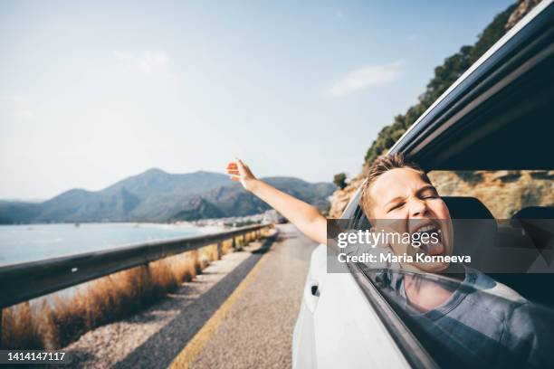 boy enjoying the wind blowing his hair in the back seat of the car. little boy looking out of car on a road trip. - kid head out car window stock pictures, royalty-free photos & images