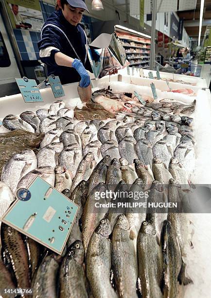 Une employée d'un super marché de l'enseigne Carrefour sert du poisson dans un rayonnage de poissons, le 15 mars 2012 à Hazebrouck. AFP PHOTO /...