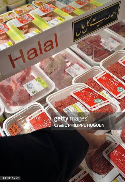 Une cliente d'un super marché de l'enseigne Carrefour choisi de la viande Halal dans un rayonnage, le 15 mars 2012 à Hazebrouck. AFP PHOTO / PHILIPPE...