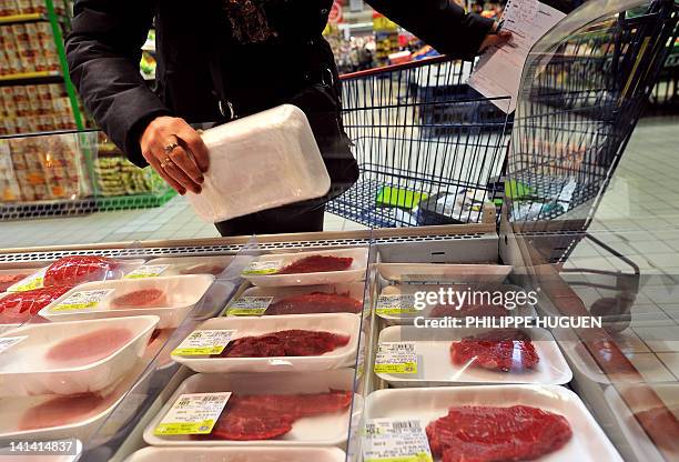 Une cliente d'un super marché de l'enseigne Carrefour choisi de la viande dans un rayonnage, le 15 mars 2012 à Hazebrouck. AFP PHOTO / PHILIPPE HUGUEN