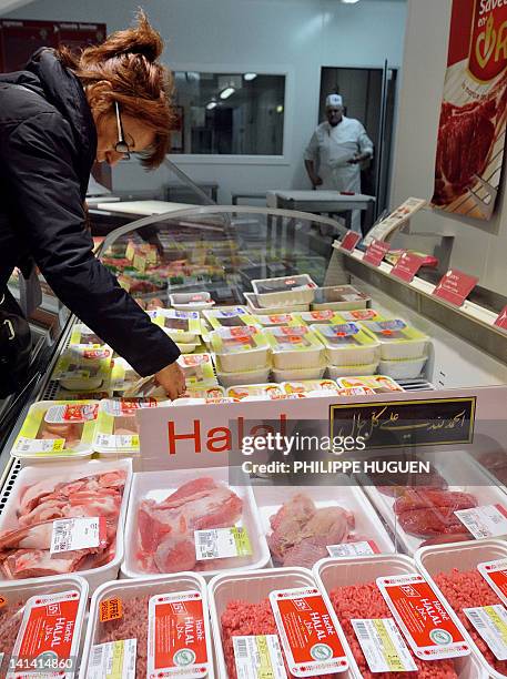 Une cliente d'un super marché de l'enseigne Carrefour choisi de la viande Halal dans un rayonnage, le 15 mars 2012 à Hazebrouck. AFP PHOTO / PHILIPPE...