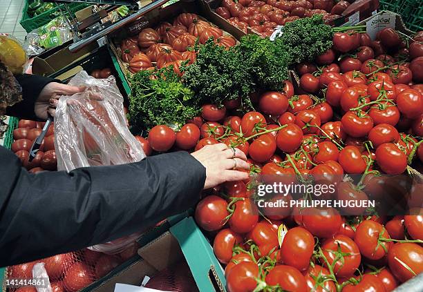 Une cliente d'un super marché de l'enseigne Carrefour choisi des tomates dans un rayonnage, le 15 mars 2012 à Hazebrouck. AFP PHOTO / PHILIPPE HUGUEN