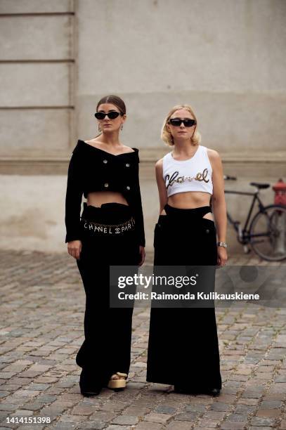 Linn Eklund wearing black wide pants, black crop jacket, Chanel chain belt and beige shoes and Fanny Ekstrand wearing black long skirt, white Chanel...