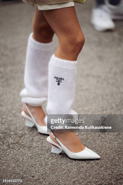 Emili Sindlev wearing long wool white Prada socks, white block heel shoes, Miu miu beige skirt, white top and green / white jacket posing outside...