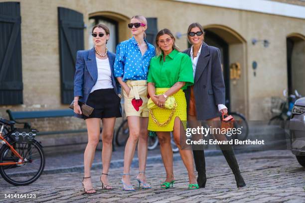 Annabel Rosendahl wears black cat eyes sunglasses, silver earrings, a gold and silver large pearls necklace, a white ribbed tank-top, a blue denim...