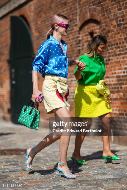 Marianne Theodorsen wears black plastic and purple velvet sunglasses from Chanel, multicolored earrings, a blue with white polka dots print pattern...