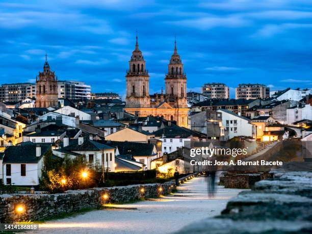 people walking on the ancient roman wall of the city of lugo at dusk. - lugo city stock pictures, royalty-free photos & images