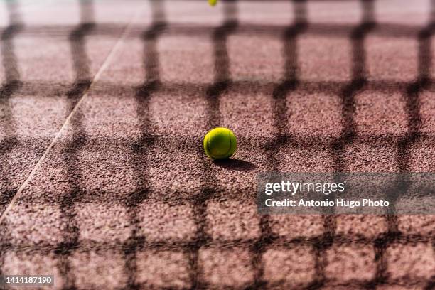 tennis ball seen through the net - tennis ball on court stock pictures, royalty-free photos & images