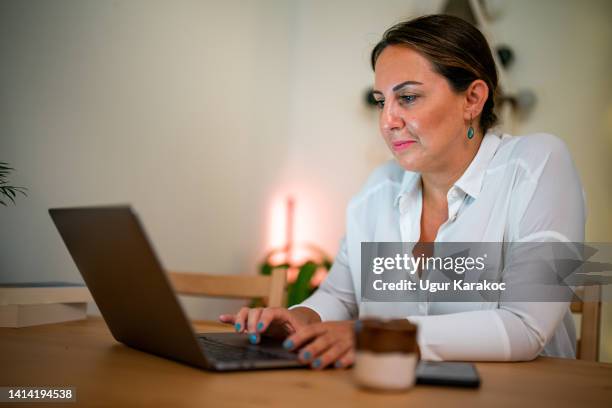 woman using laptop at home office - turkse etniciteit stockfoto's en -beelden