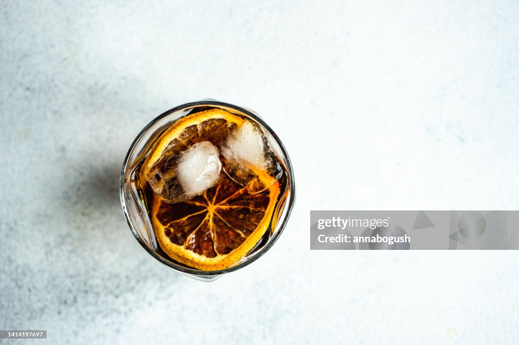 Overhead view of a cola drink with ice cubes and slices of orange