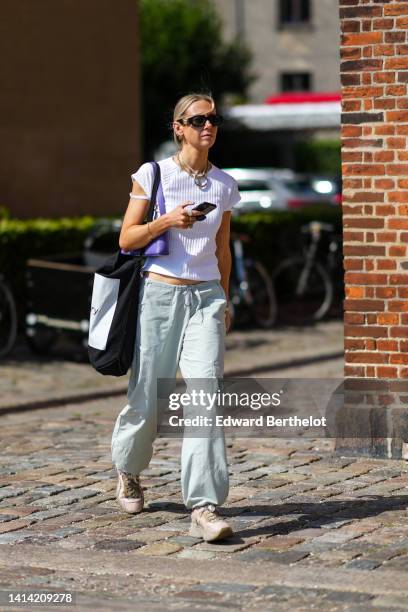 Guest wears black sunglasses from Versace, gold and silver earrings, a gold large necklace, a white cordon with large silver circle pendant necklace,...