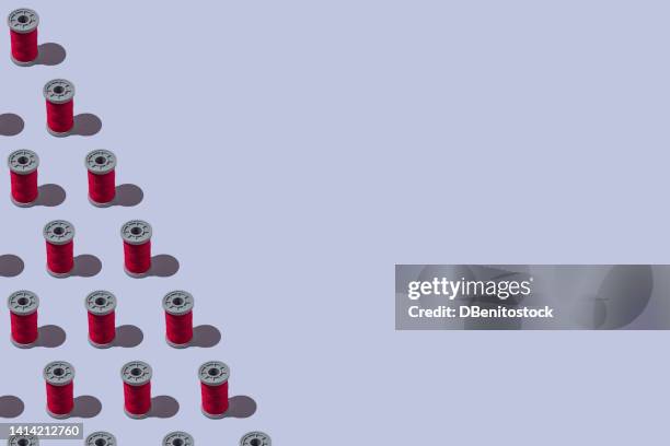 pattern of red industrial sewing thread spools, on the left side, on teal gray background. concept of design, textile, sewing, tailoring, dressmaker and embroidery. - roter faden stock-fotos und bilder