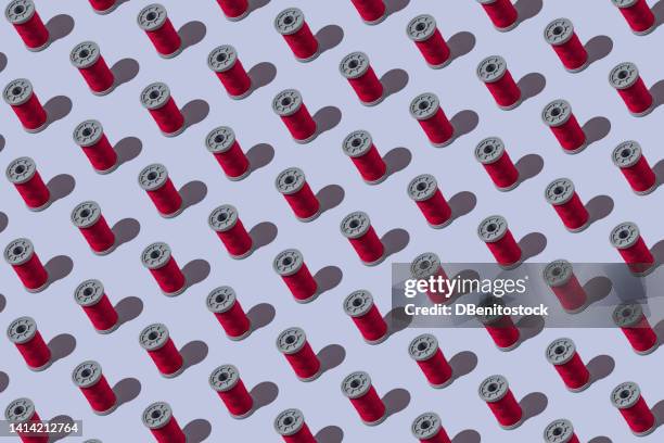 pattern of red industrial sewing thread spools on teal gray background. concept of design, textile, sewing, tailoring, dressmaker and embroidery. - thread sewing item stock pictures, royalty-free photos & images