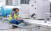 Female engineer inspects and controls the cooling system of a large factory air conditioner.