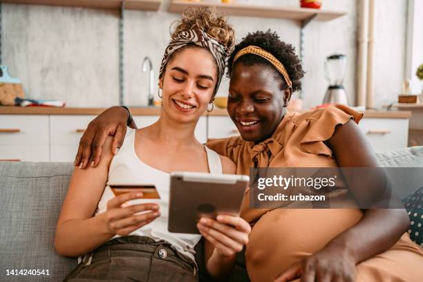 coppia lesbica incinta che acquista online usando il tablet - lgbt mobile foto e immagini stock