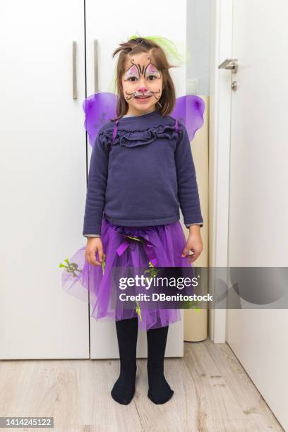 black-haired girl with kitty makeup and witch wings on halloween. carnival, halloween, masquerade, makeup and party celebration and tradition concept. - children role playing crime stock-fotos und bilder