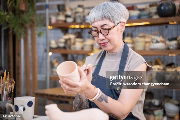 femal painting a ceramic cup with a brush. - painting pottery stock pictures, royalty-free photos & images