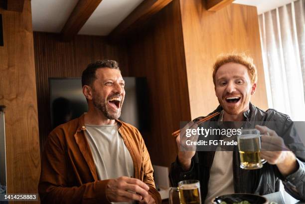 friends talking and eating asian food at home - male friends drinking beer stock pictures, royalty-free photos & images