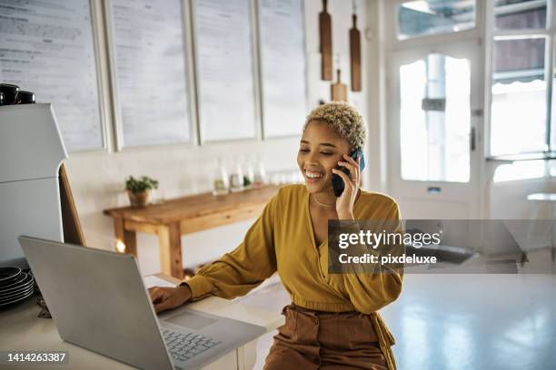 business owner on phone call taking online orders suing a laptop in a coffee shop. cheerful female entrepreneur of local cafe or restaurant chatting with customer and ordering supplies online - small restaurant stock pictures, royalty-free photos & images