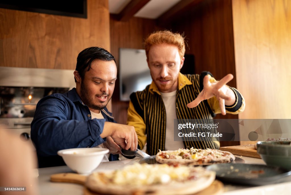 Amigos que hacen pizza en casa, incluida una persona con necesidades especiales