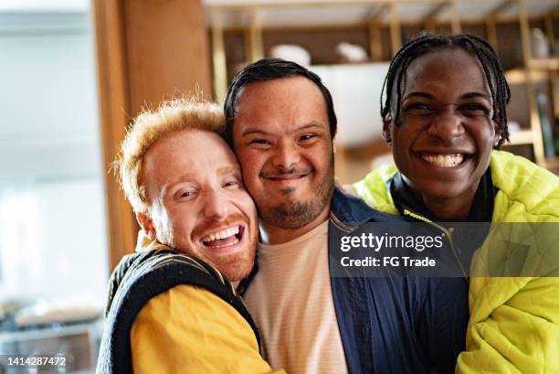 portrait of a disabled young man and his friends embraced at home - special needs stock pictures, royalty-free photos & images