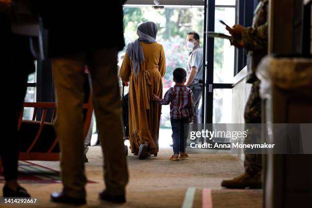 An Afghan national and her son walk through the National Conference Center , which in recent months has been redesigned to temporarily house Afghan...