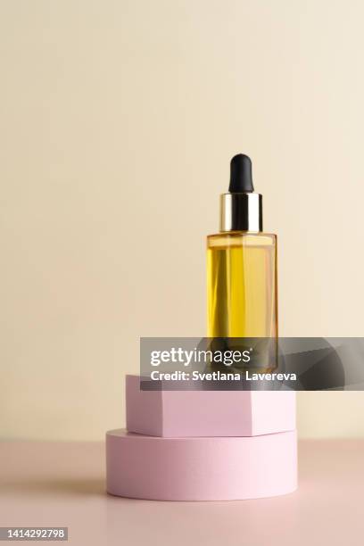 a glass dropper bottle with a pippette with black rubber tip on the white podiums on the light background. nature skin concept. organic spa cosmetics. trendy concept. - cosmetic jar stockfoto's en -beelden