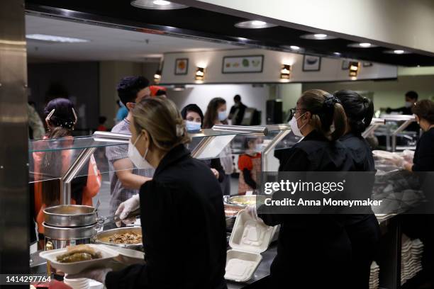 Kitchen staff serve food to Afghan nationals in the dining room of the National Conference Center , which in recent months has been redesigned to...