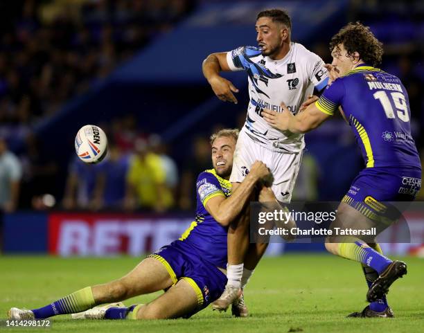 Corey Norman of Toulouse is challenged by James Harrison and Robbie Mulhern of Warrington Wolves during the Betfred Super League between Warrington...