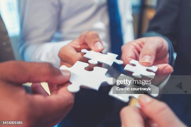 gruppe von geschäftsleuten, die ein puzzleteil halten. - jigsaw pieces stock-fotos und bilder