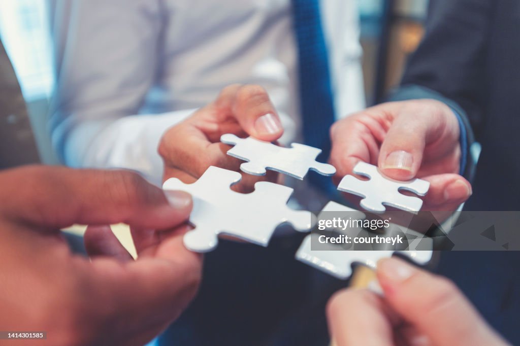 Group of business people holding a jigsaw puzzle pieces.