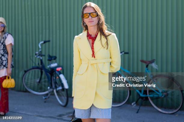 Guest is seen wearing yellow belted blazer, striped shorts outside Stine Goya during Copenhagen Fashion Week Spring/Summer 2023 on August 10, 2022 in...