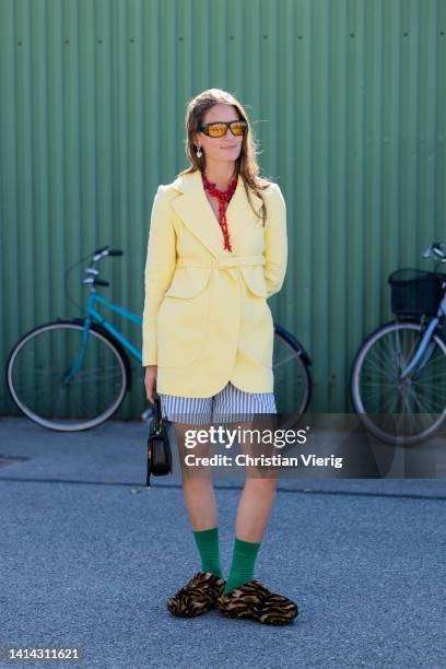 Guest is seen wearing yellow belted blazer, striped shorts outside Stine Goya during Copenhagen Fashion Week Spring/Summer 2023 on August 10, 2022 in...