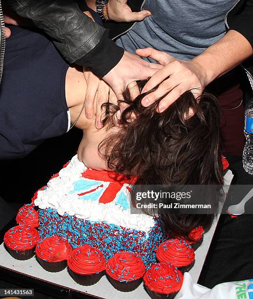 Harry Styles of the band One Direction has his face pushed into a cake by bandmates while visiting The Elvis Duran Z100 Morning Show for a pre-taped...