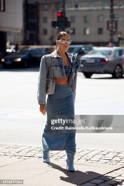 Nina Sandbech wearing long denim maxi skirt, matching cropped top and matching cropped denim jacket with a flower, light blue / denim bag and...