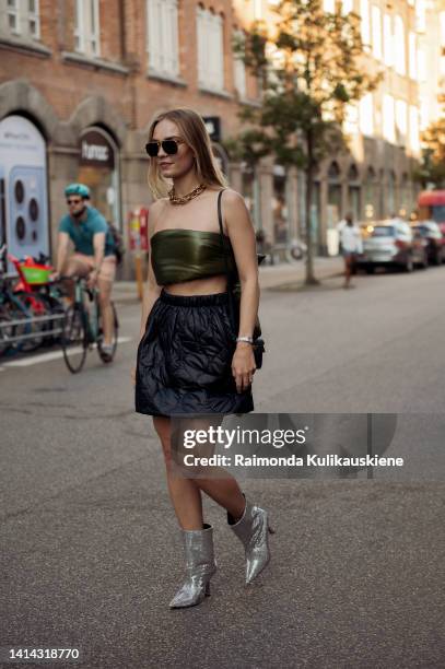 Guest wearing black puffy skirt, army green bound top, black bag and silver shiny high heels posing outside Baum und Pferdgarten during Copenhagen...