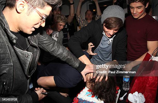 Harry Styles of the band One Direction has his face pushed into a cake by bandmates while visiting The Elvis Duran Z100 Morning Show for a pre-taped...