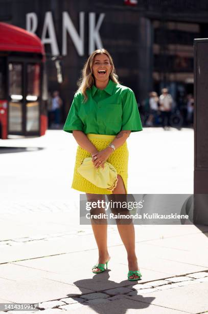 Janka Polliani wearing knitted yellow skirt, green short sleeve shirt, green shoes and yellow bag posing outside Holzweiler during Copenhagen fashion...