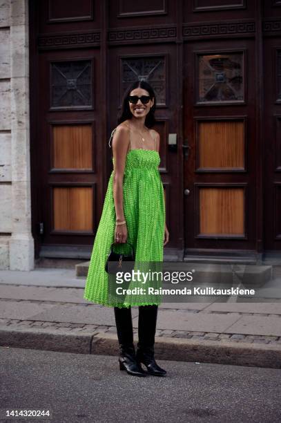 Babba C Rivera wearing green dress, long black boots and black bag posing outside Baum und Pferdgarten during Copenhagen fashion week Spring / Summer...