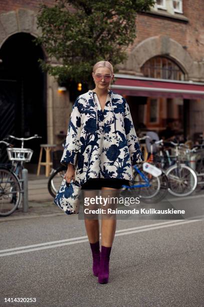 Guest wearing blue and white pattern dress / coat, same fabric bag and purple high heel boots posing outside Baum und Pferdgarten during Copenhagen...