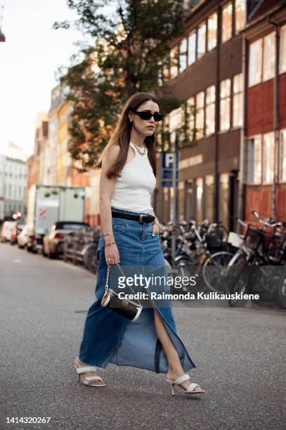 Annabel Rosendahl wearing white top, long maxi denim skirt and Louis Vuitton bag posing outside Baum und Pferdgarten during Copenhagen fashion week...