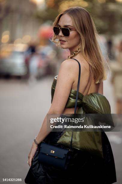 Guest wearing black puffy skirt, army green bound top, black bag and silver shiny high heels posing outside Baum und Pferdgarten during Copenhagen...