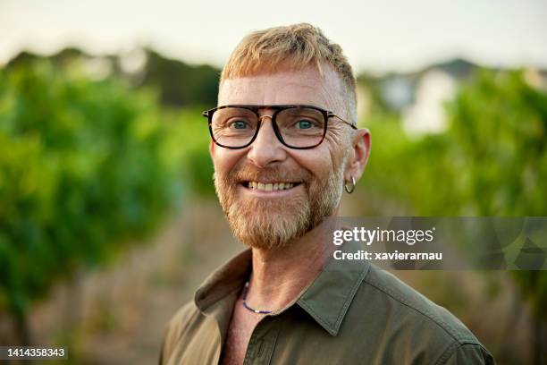 retrato de un alegre hombre barbudo en el viñedo al atardecer - hombre gay fotografías e imágenes de stock