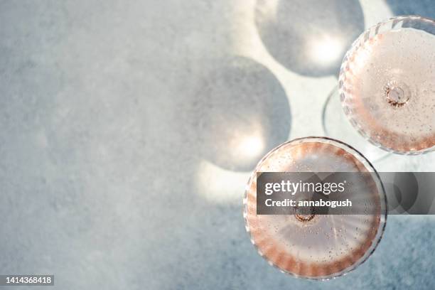 overhead view of two glasses of pink champagne in champagne coupe glasses - prosecco stock pictures, royalty-free photos & images